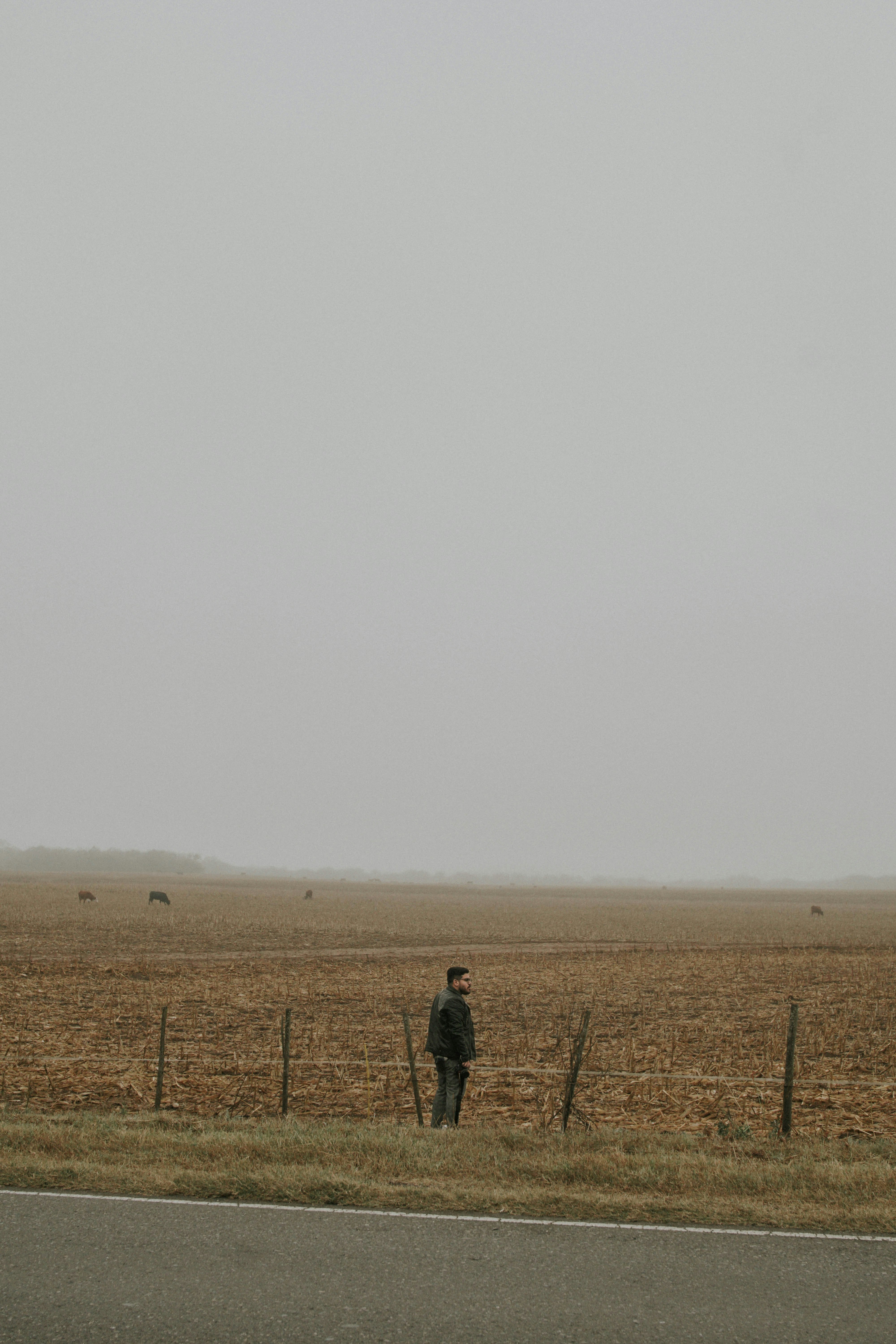 man wearing black jacket standing on brown field